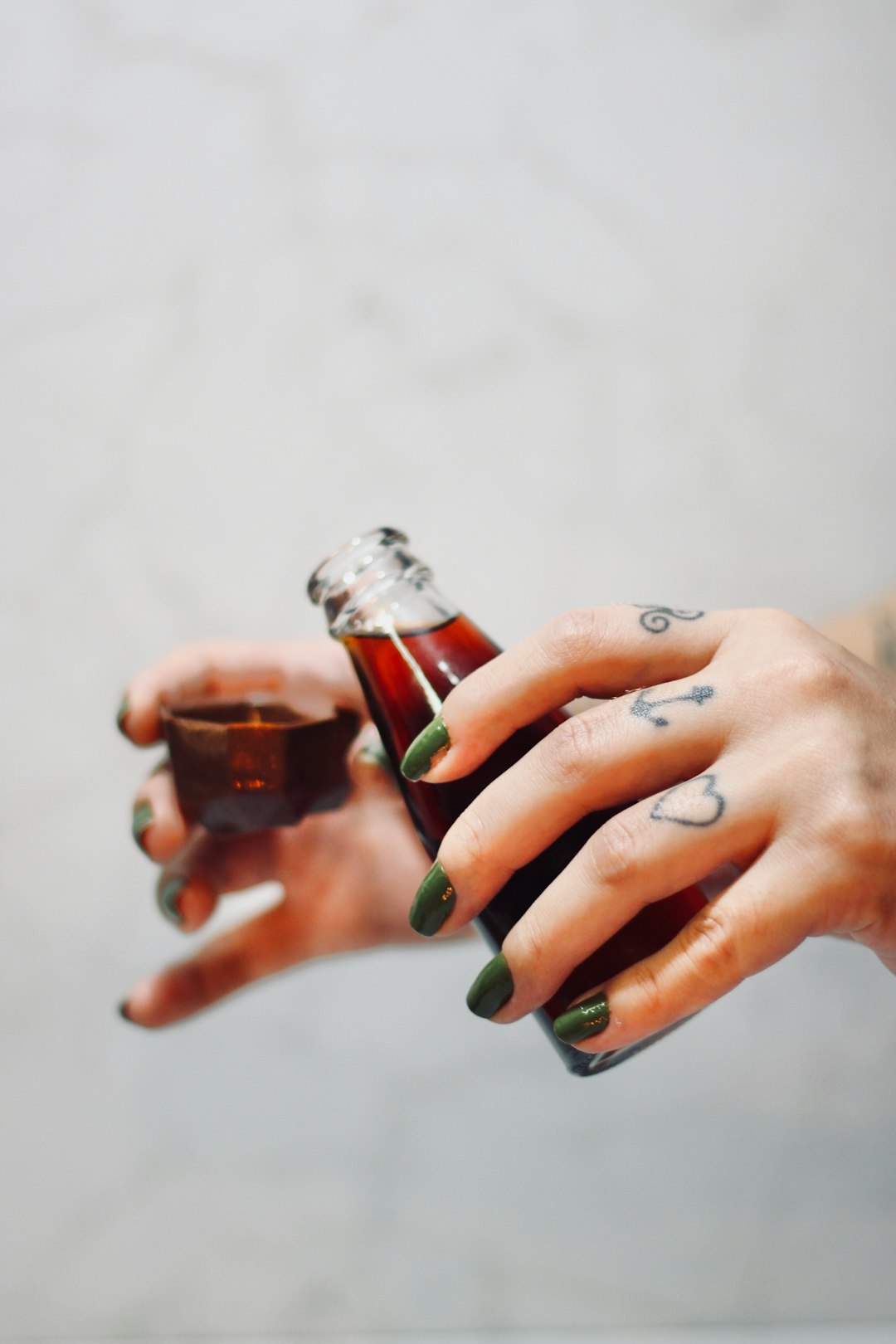 person holding clear glass bottle with red liquid