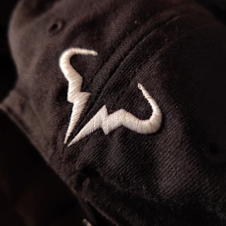 An elegant thobe draped over a richly textured surface with lightning bolt motifs subtly embroidered along the sleeves.