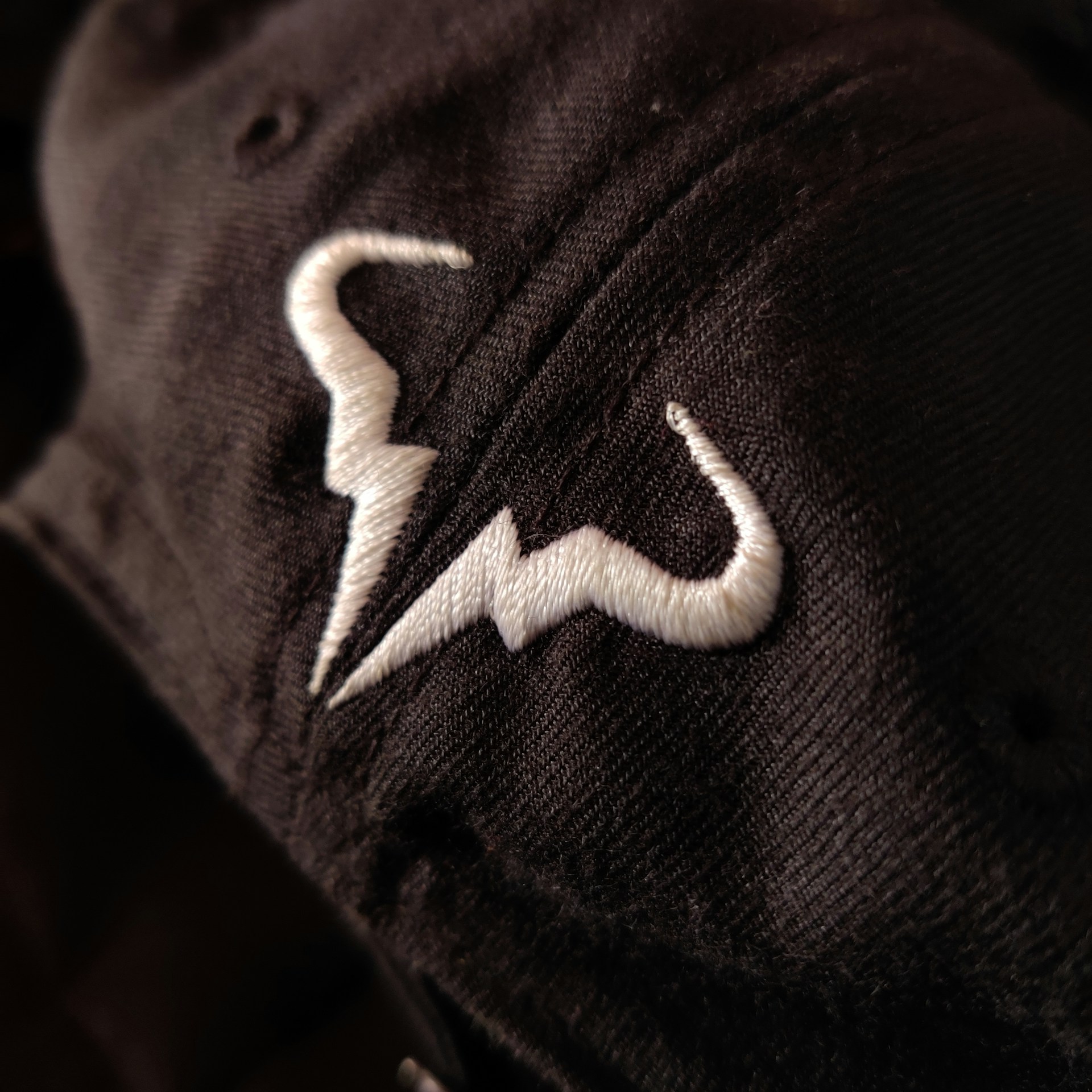 Close-up of intricate voodoo symbols embroidered on dark fabric, blending into a gentle fade background.