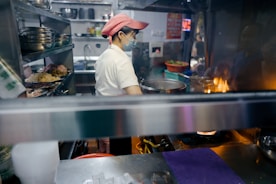 man in white shirt and brown hat standing in front of food counter
