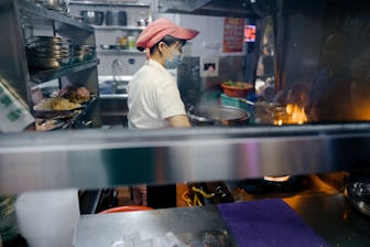 man in white shirt and brown hat standing in front of food counter