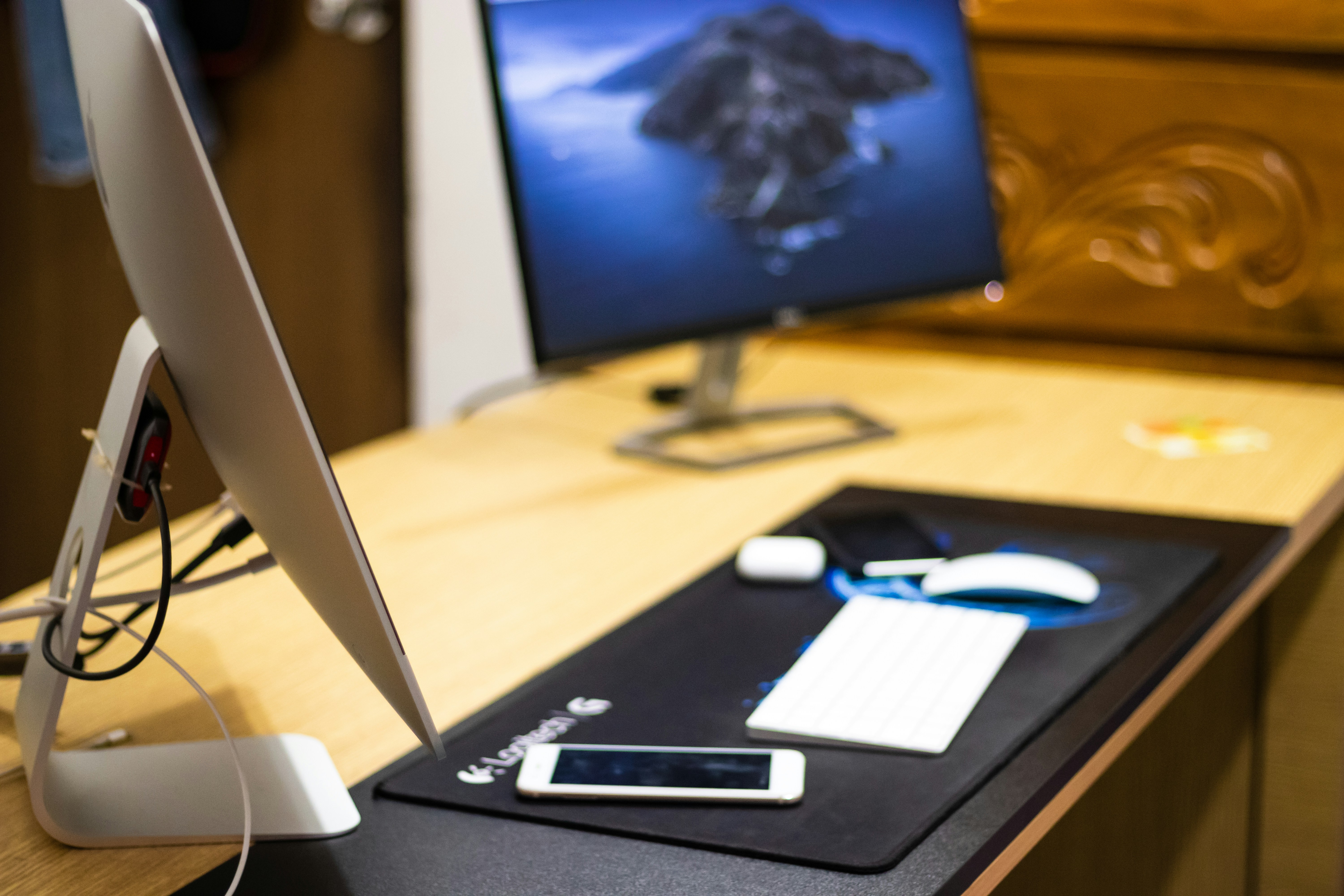 Laptop and tech devices on dark desk with blue ambient lighting