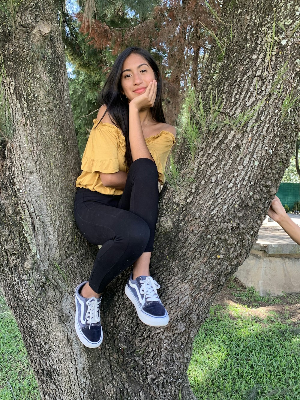woman in yellow shirt and black pants sitting on tree trunk