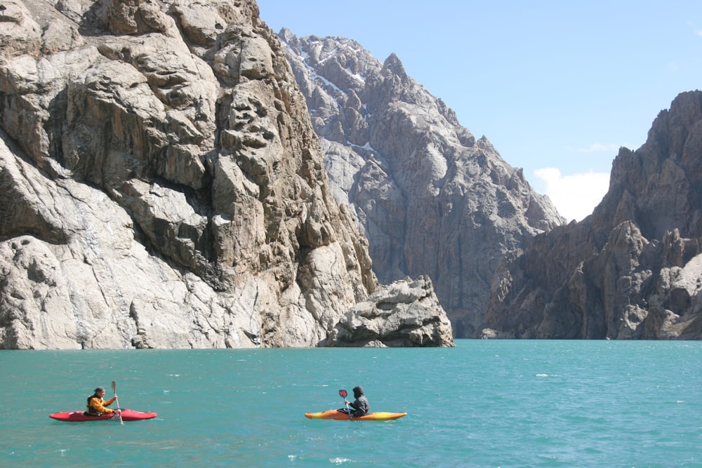 Persona montada en kayak rojo en el mar cerca de las Montañas Rocosas durante el día