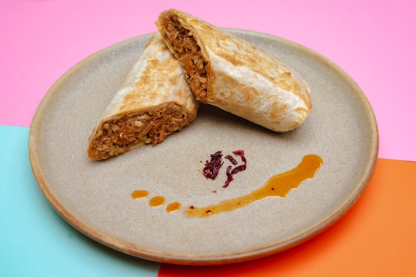 A colorful plate featuring a sliced campechano burrito with beans and rice on the side, ready to enjoy.