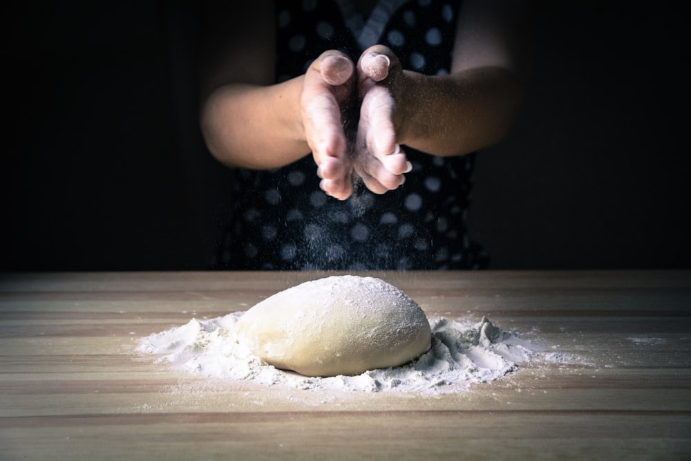person holding dough on white table