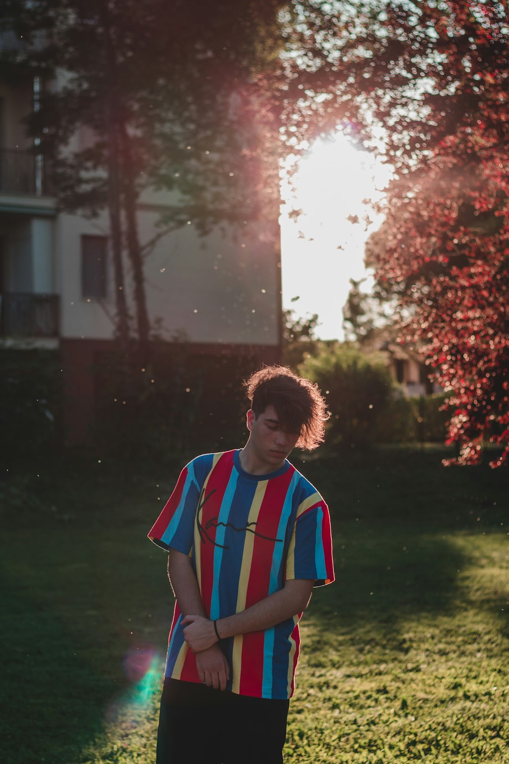 man in blue white and red striped polo shirt standing on green grass field during daytime