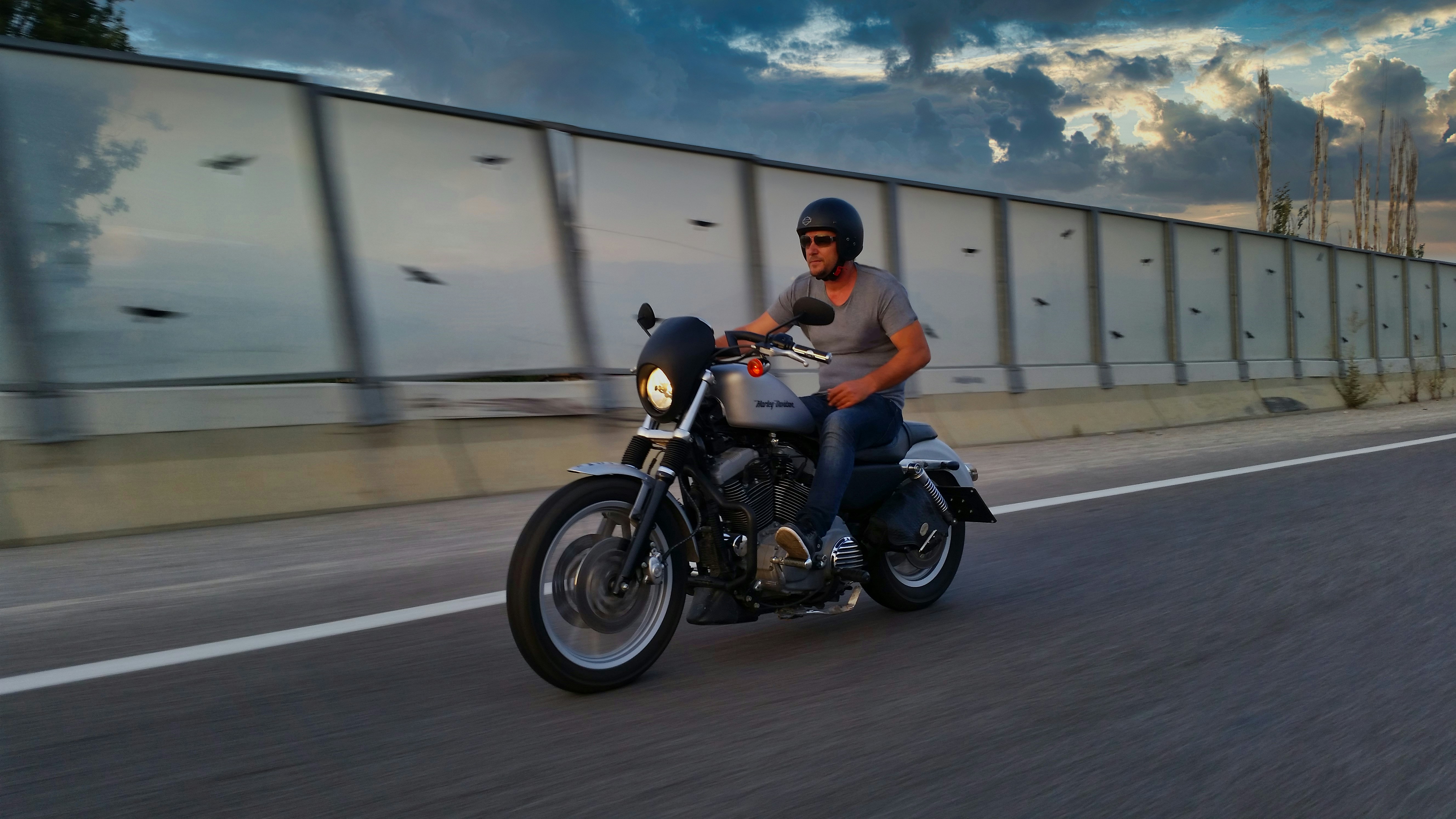 주황색 폴로 셔츠를 입은 남자가 검은색 오토바이를 타고 있다