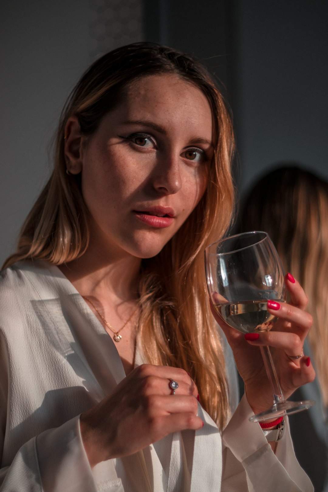 woman in white blazer holding wine glass