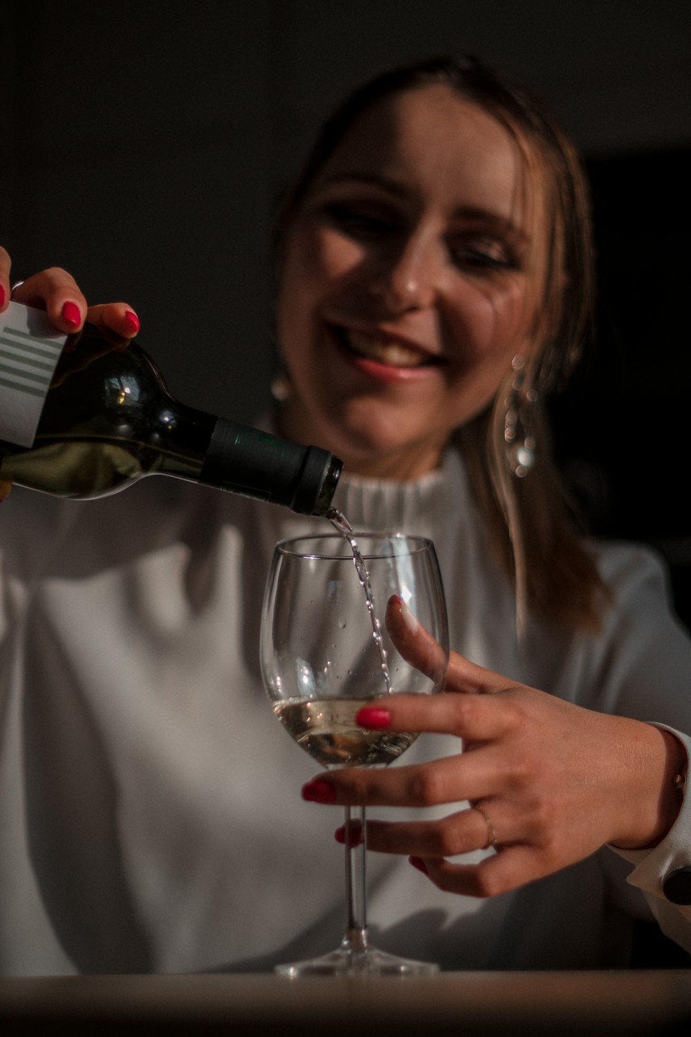 smiling woman holding wine bottle and wine glass