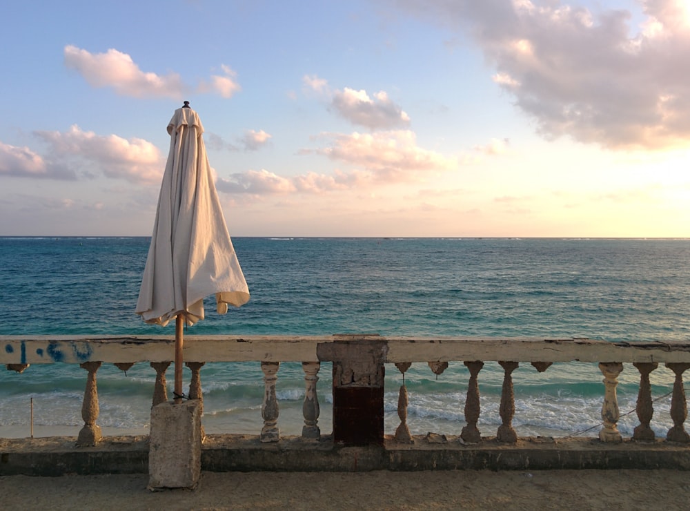 white textile on brown wooden fence near sea during daytime