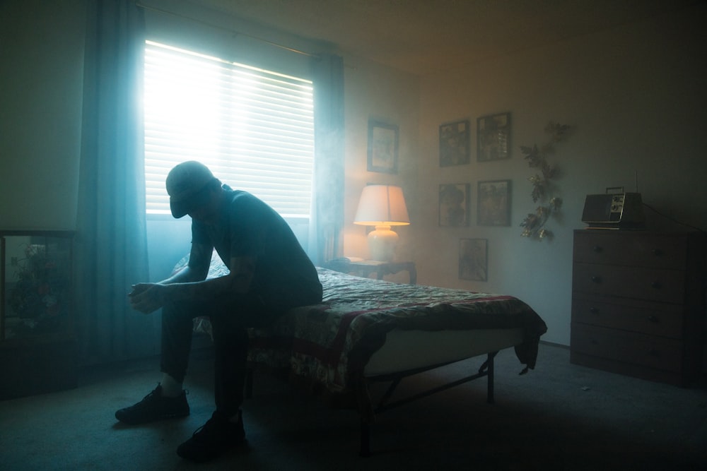 man in black jacket sitting on bed