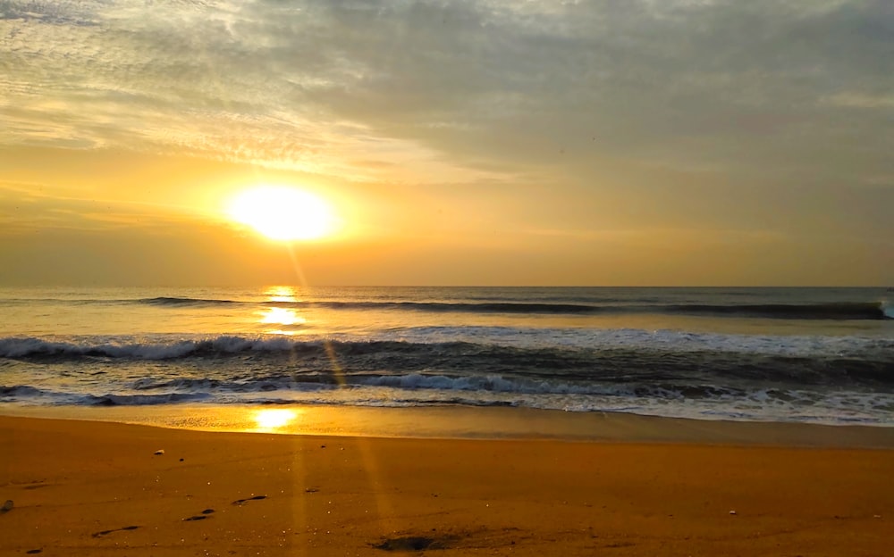 sea waves crashing on shore during sunset