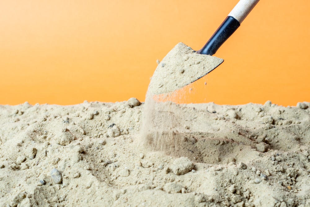 black and red shovel on white sand