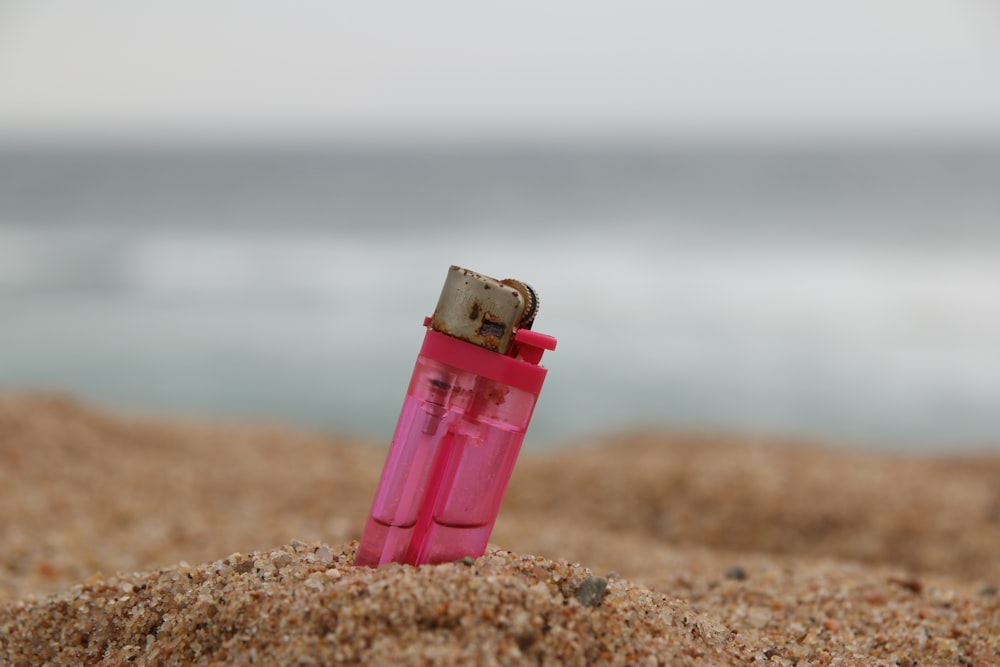 pink disposable lighter on brown sand