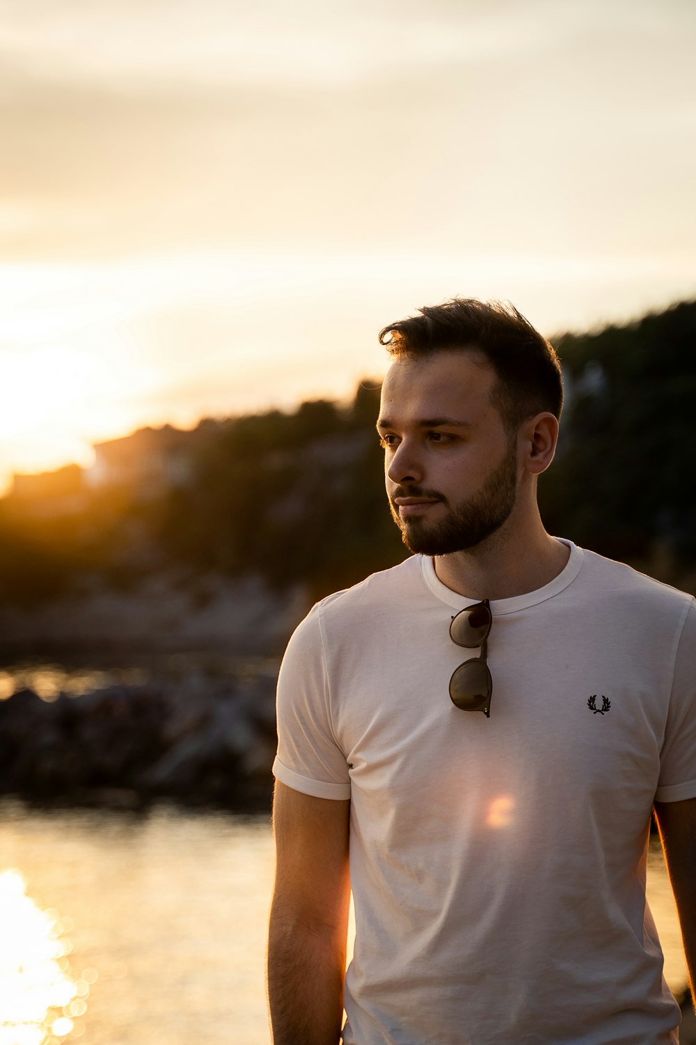 man in white crew neck t-shirt standing near body of water during daytime