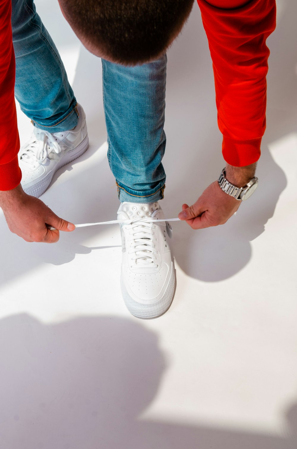 a person tying a pair of white sneakers