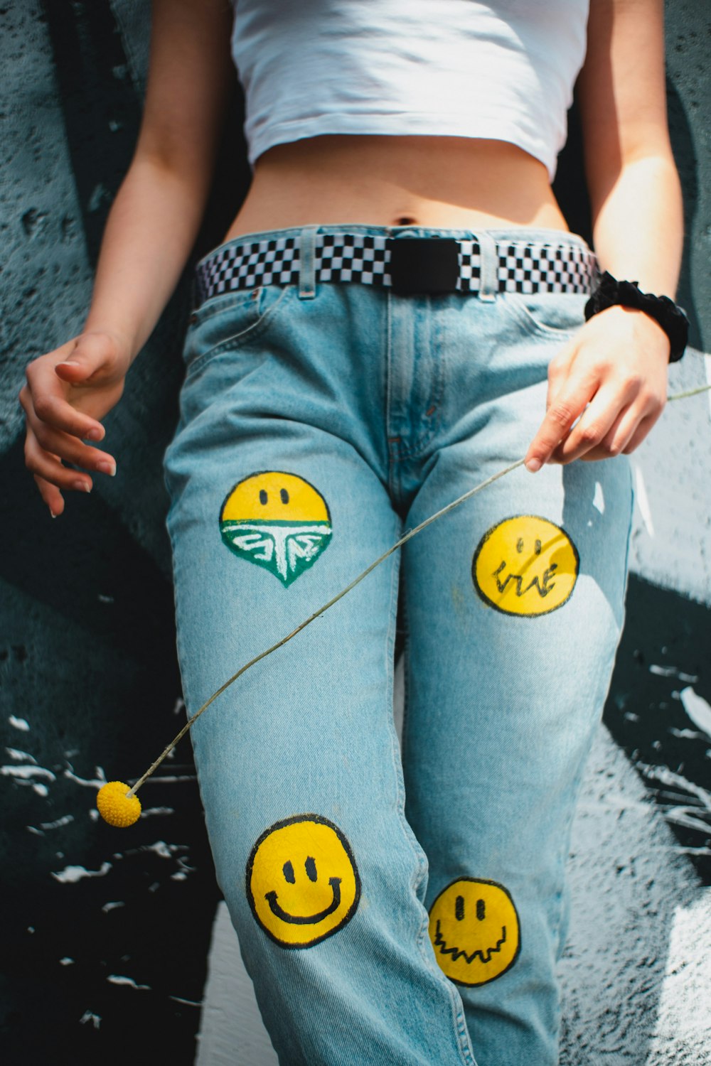 a woman wearing jeans with smiley faces painted on them
