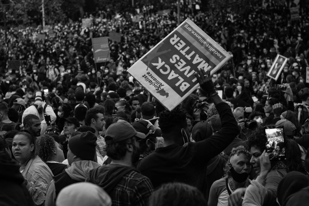 grayscale photo of people holding a signage