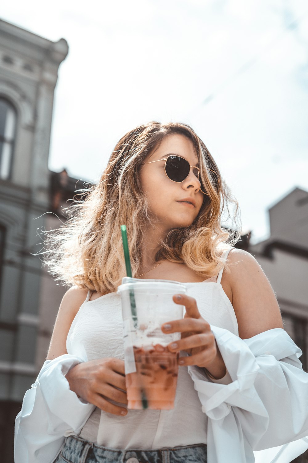 woman in white tank top holding clear plastic cup