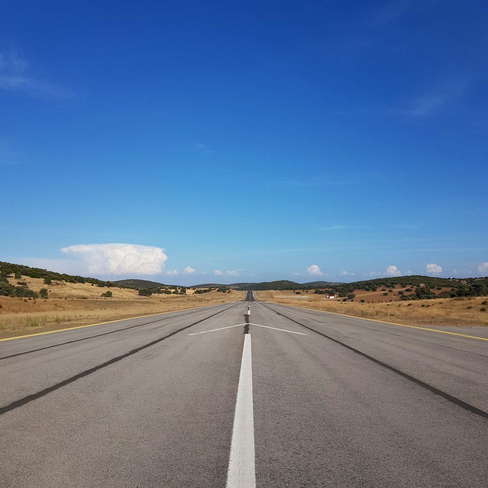 昼間の青空に覆われた灰色のアスファルト道路