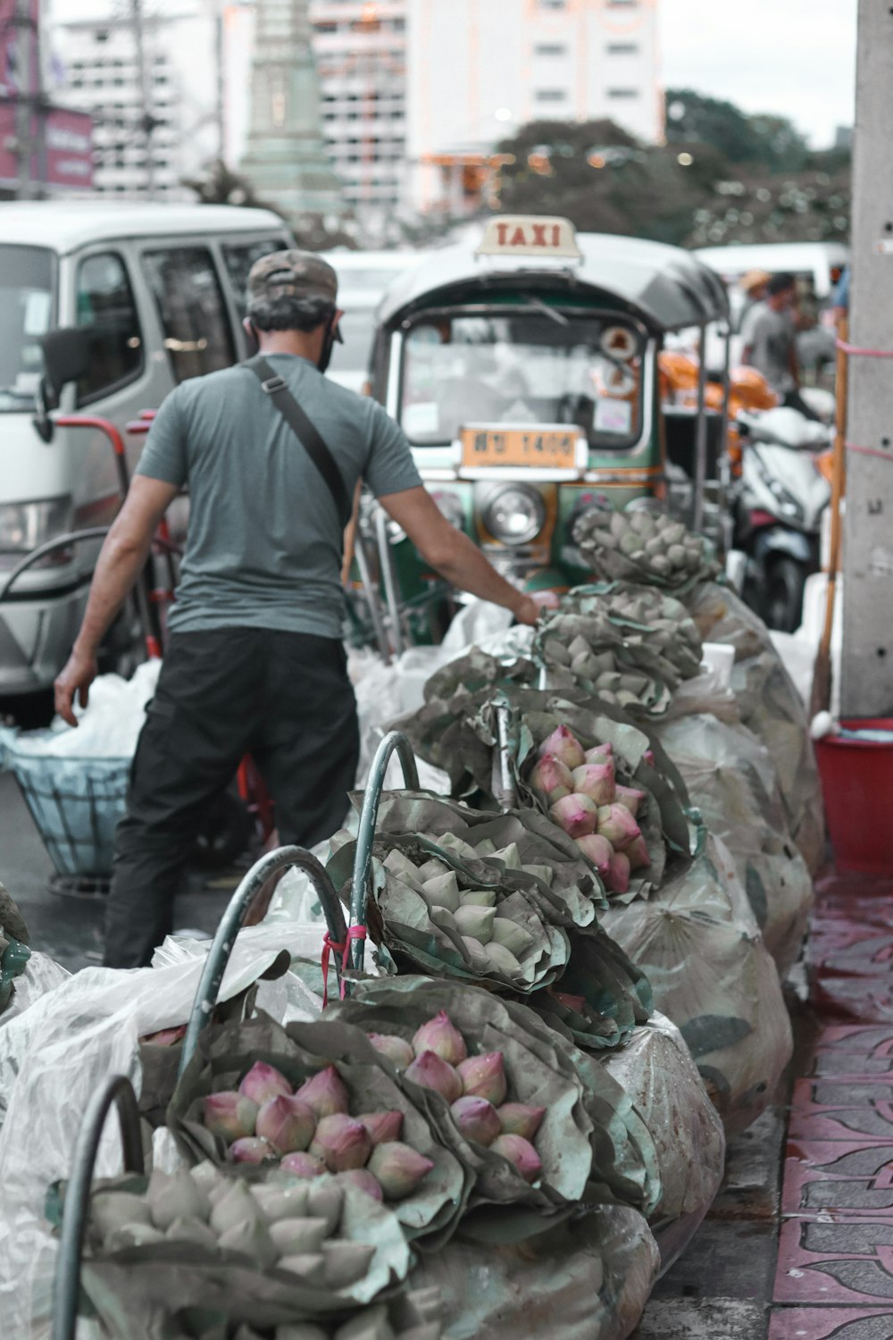 man in black t-shirt and gray pants standing in front of fruit stand