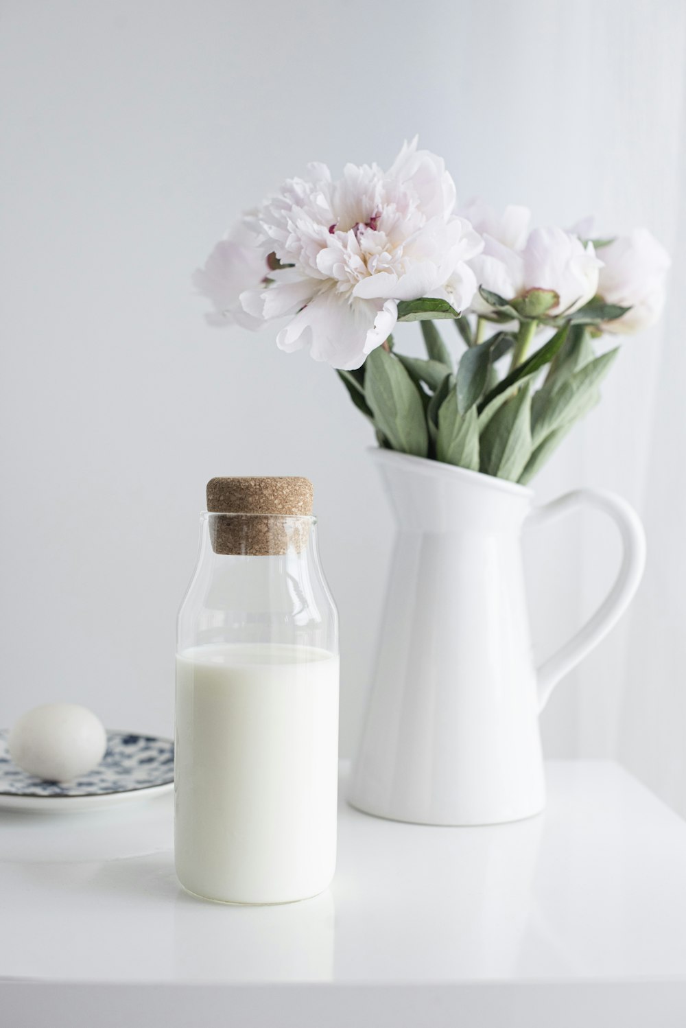 white and pink flowers in white ceramic pitcher