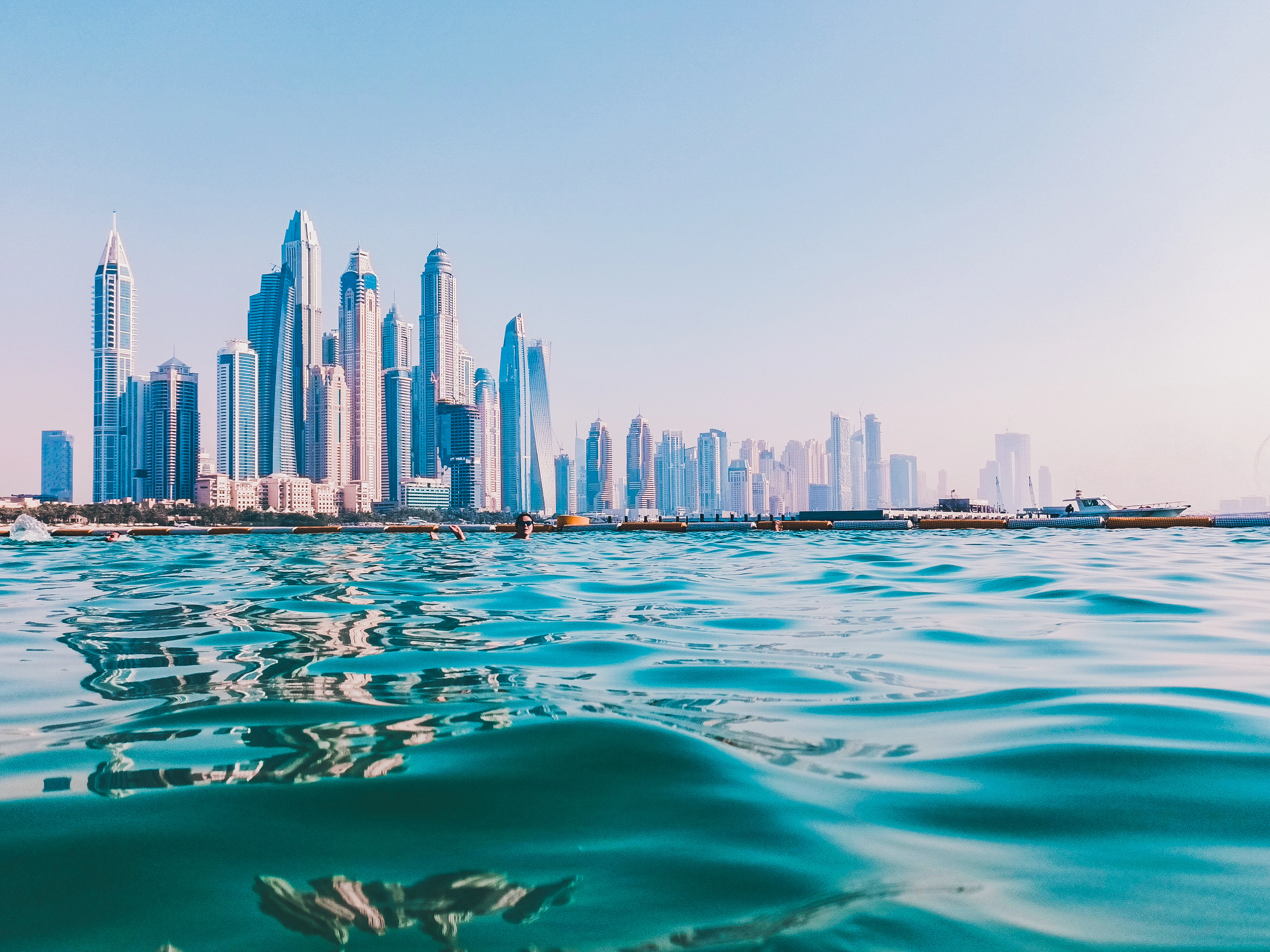 The Dubai Marina skyline seen low over the surface of turquoise water.