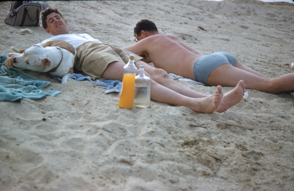 woman in blue and white bikini lying on white sand beach during daytime