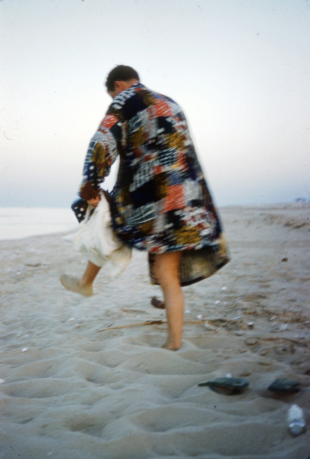 man in red blue and white tribal dress walking on beach during daytime