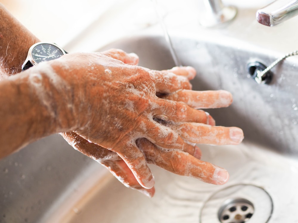 persona che si lava le mani sul lavandino