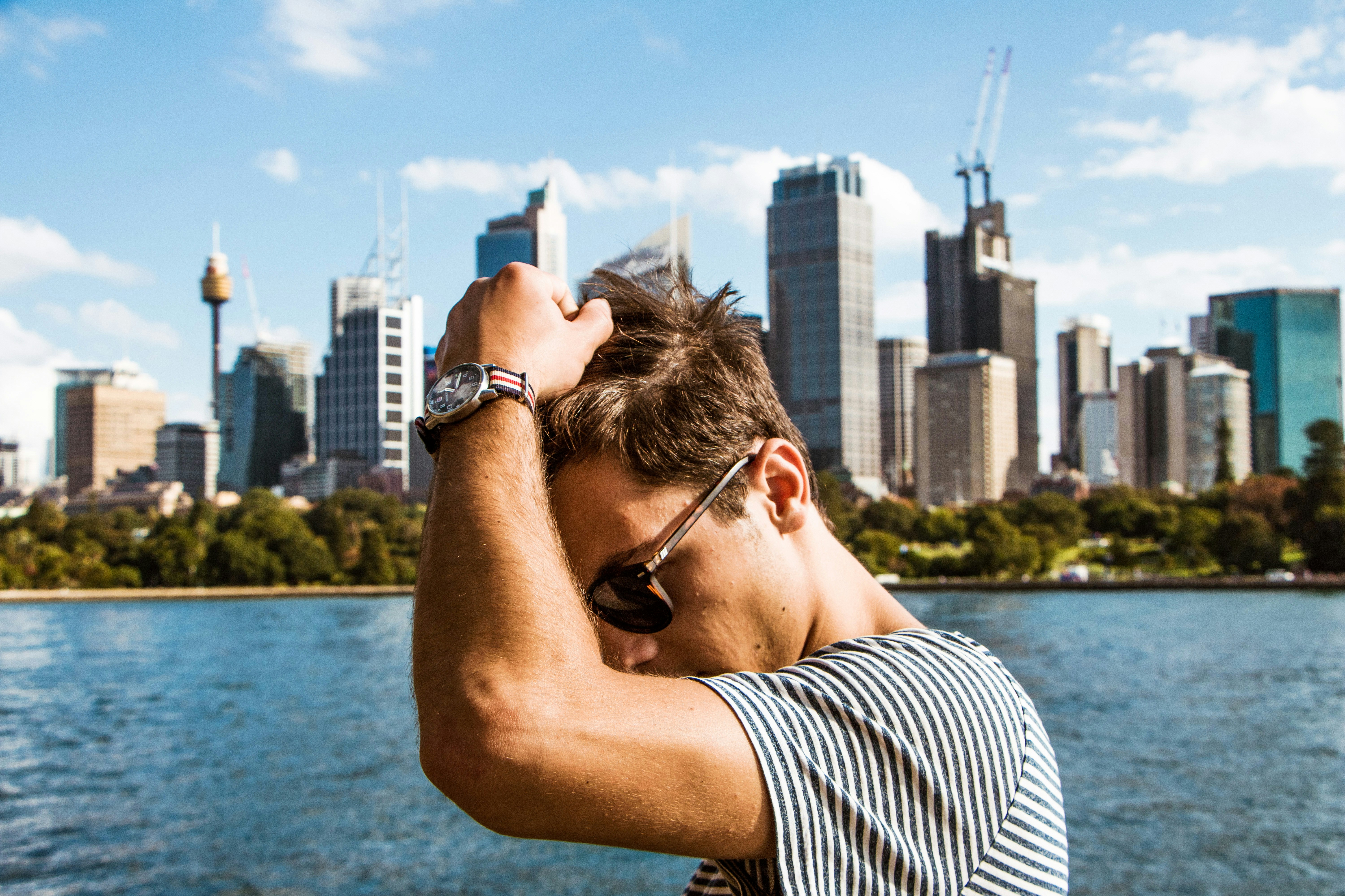 man in black and white striped shirt wearing black sunglasses looking at city buildings during daytime