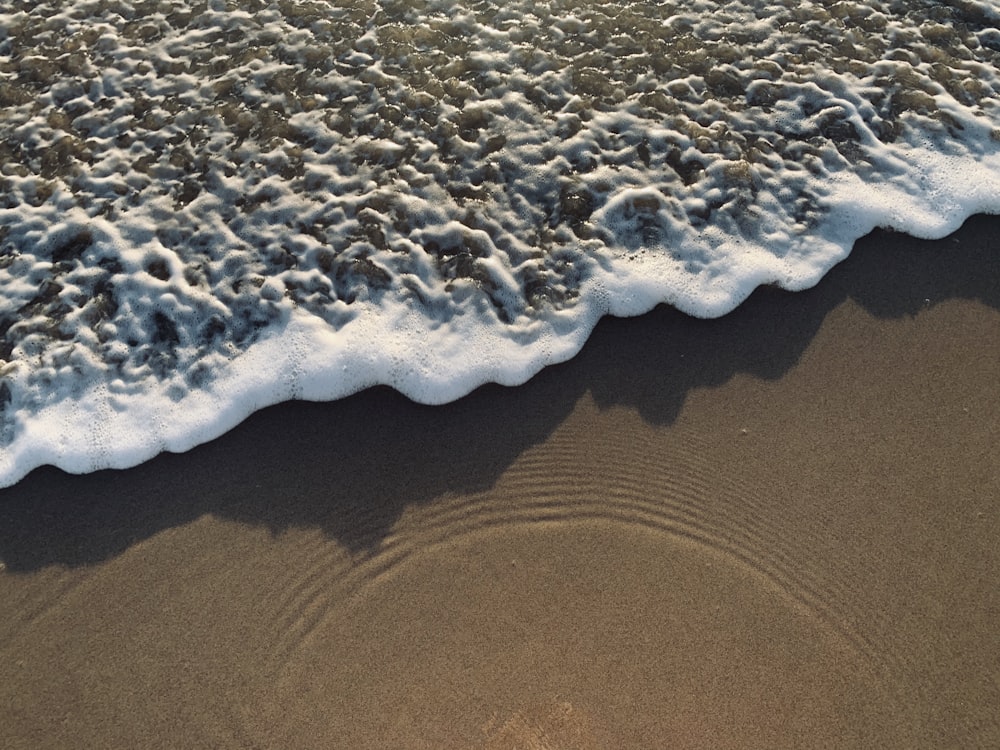 white and black sea waves on brown sand