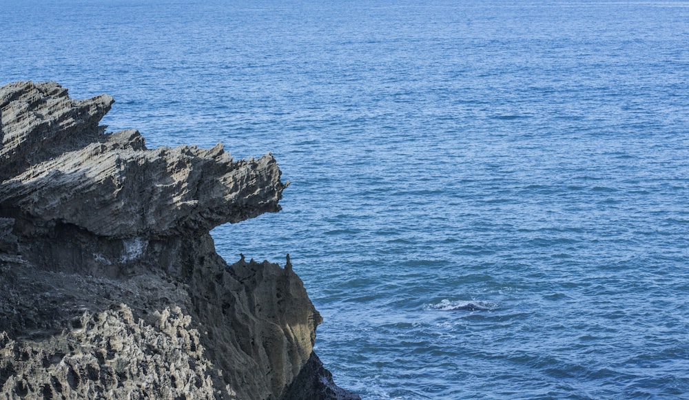 brown rocky mountain beside blue sea during daytime