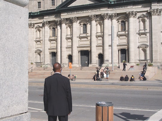 man in black coat standing on gray concrete floor during daytime in Mary, Queen of the World Cathedral Canada