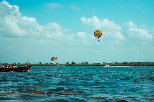 people riding red and yellow parachute over blue sea under blue sky during daytime in Tanjung Benoa Indonesia