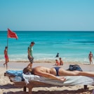 woman in black and white bikini lying on white sand beach during daytime