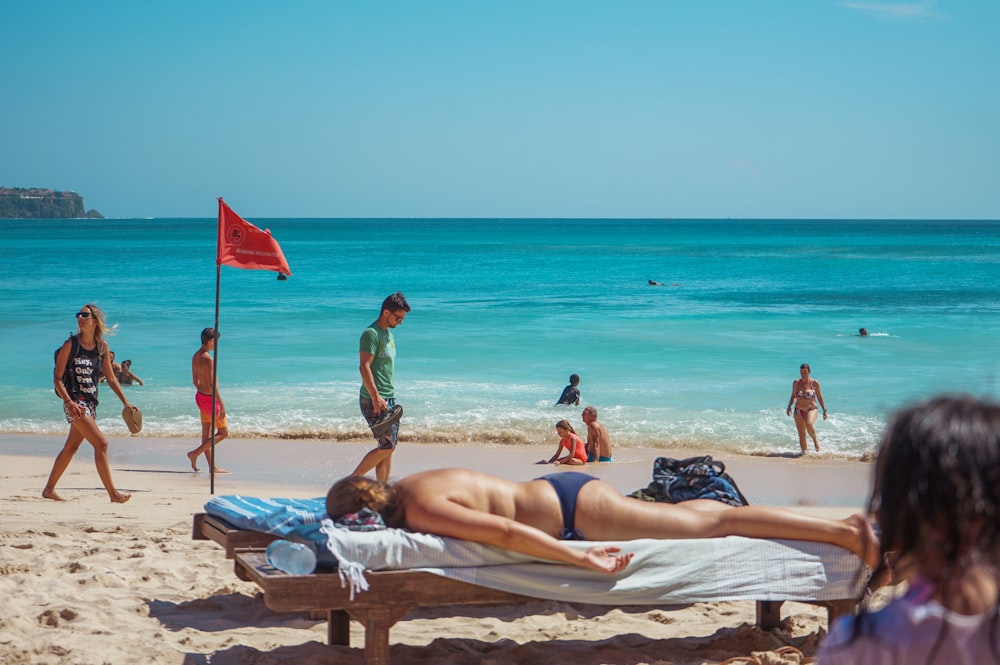 woman in black and white bikini lying on white sand beach during daytime