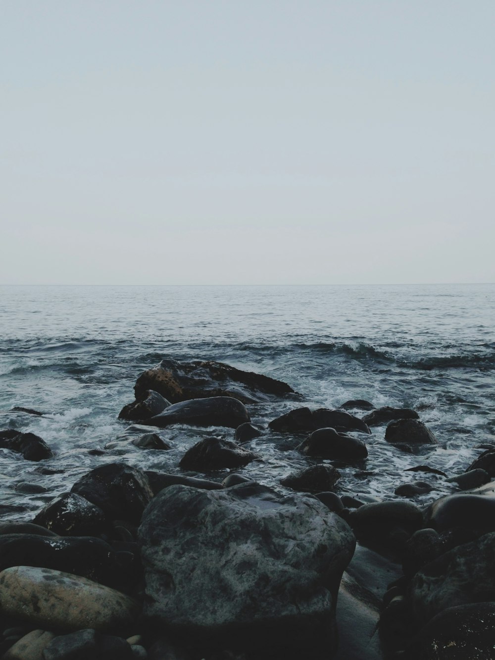 rocky shore with sea waves crashing on shore during daytime