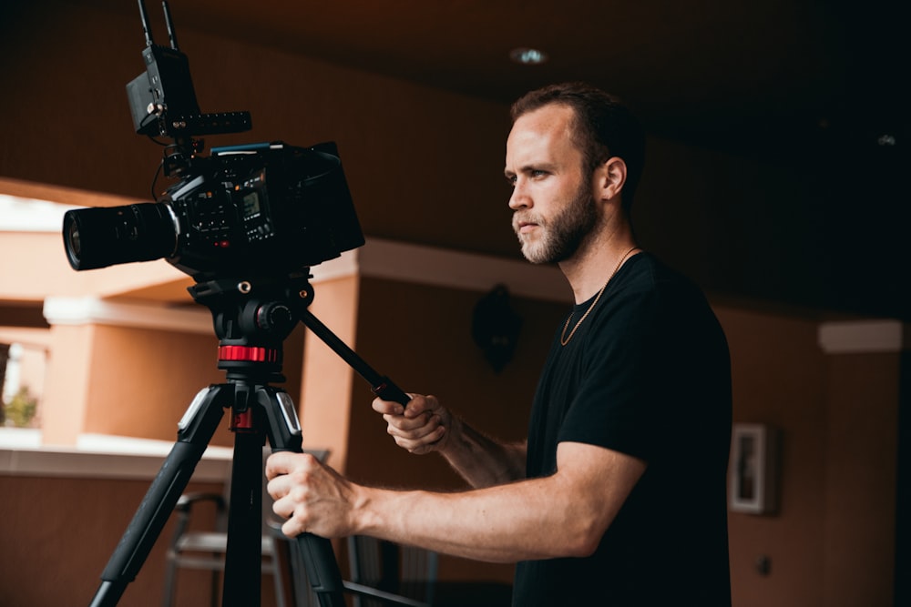 man in black crew neck t-shirt holding black camera