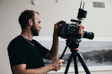 man in black crew neck t-shirt holding black dslr camera