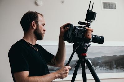 man in black crew neck t-shirt holding black dslr camera