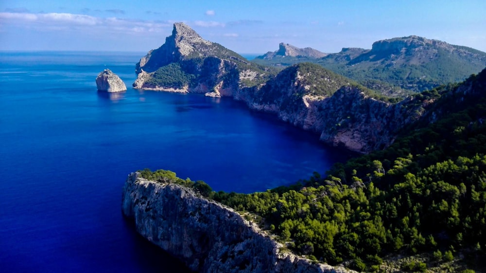 grüner und brauner Berg neben blauem Meer unter blauem Himmel tagsüber