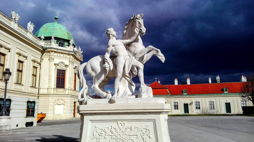 Mann reitet Pferdestatue in der Nähe des Gebäudes während des Tages