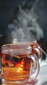 A close-up of hands holding a cup of chamomile tea with steam rising.