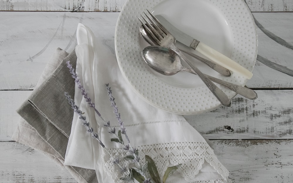 Fourchette et couteau à pain en acier inoxydable sur plaque en céramique blanche