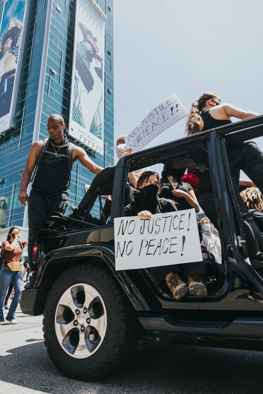 woman in black sleeveless dress standing on black and white jeep wrangler