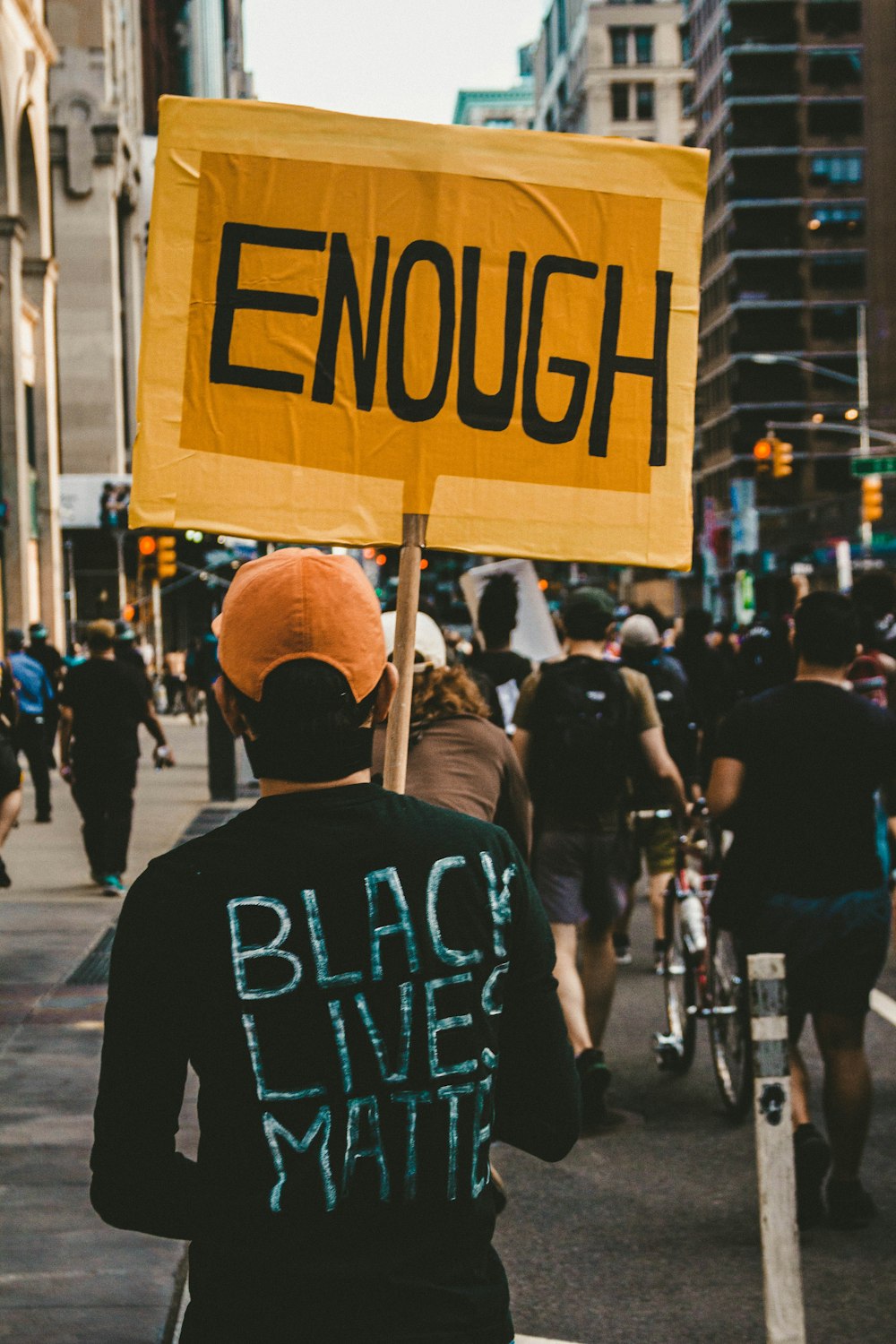 man in black and white crew neck shirt wearing brown cap walking on street during daytime