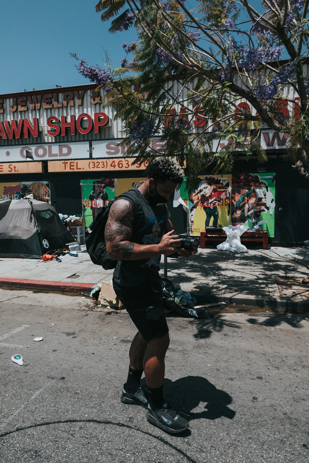 man in black t-shirt and black shorts holding black dslr camera