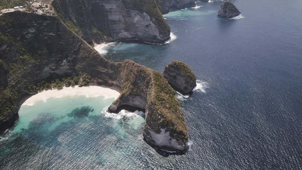 aerial view of green and brown rock formation on body of water during daytime